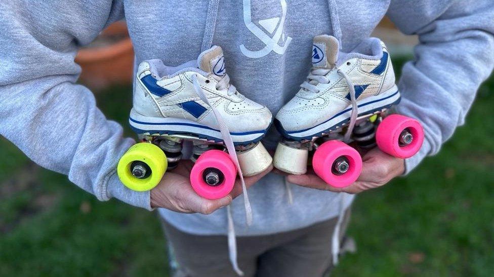 Emily Allard holding skates her children used