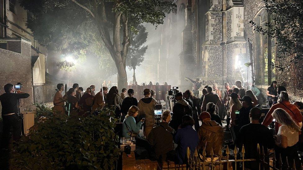 St Lawrence's Church in Ipswich flanked by actors with shields and a film crew