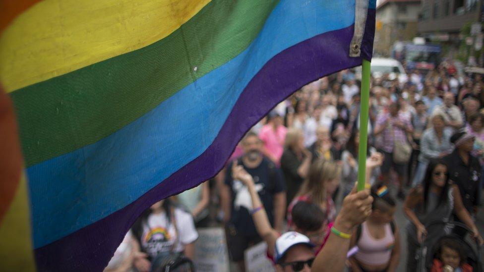 A man holds a pride flag at a rally in Toronto