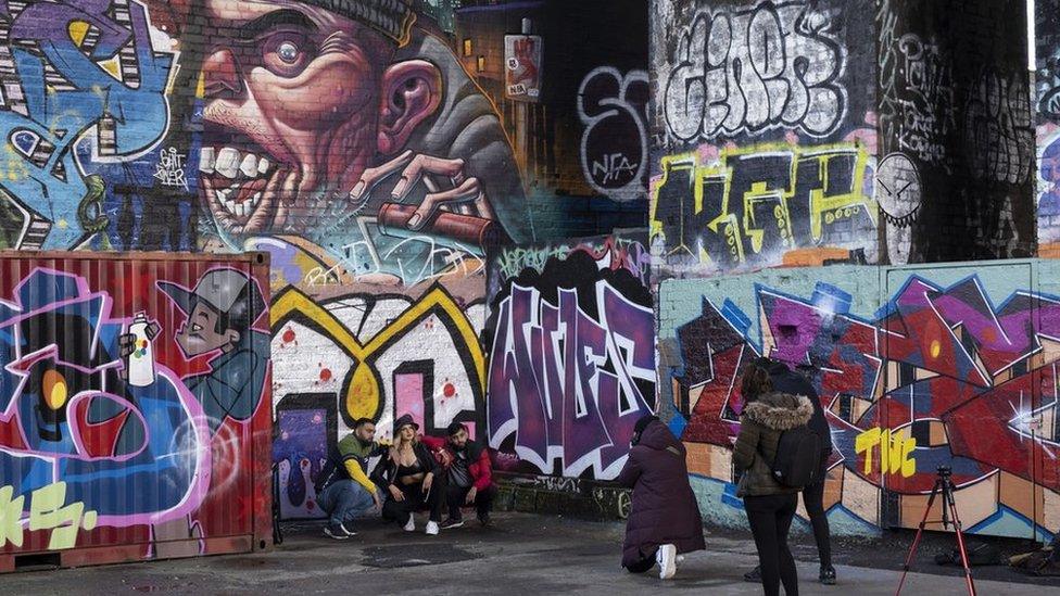 Arches covered in graffiti and some people posing for a picture