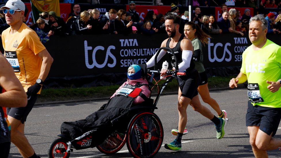 A woman is pushed in a chair by a man