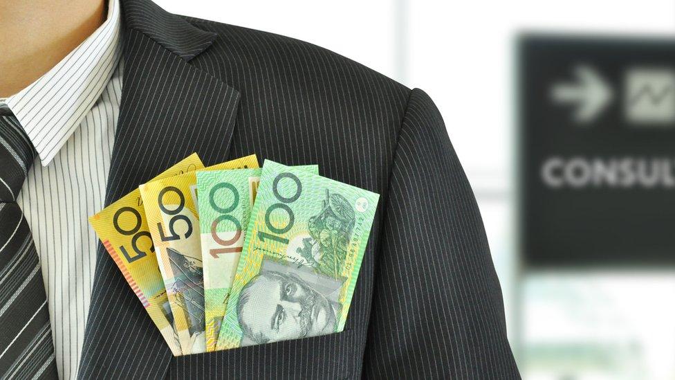 Australian money sticking out of the pocket of a man wearing a suit