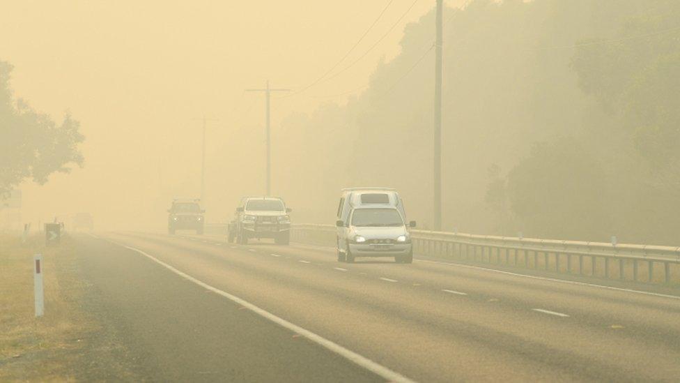 Cars evacuate through thick smoke caused by fires in Victoria