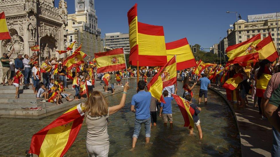 Image shows demonstrators holding Spanish flags during a protest against Catalonian independence on October 7