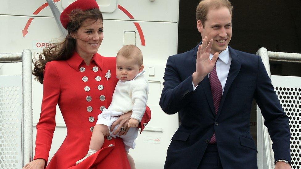 Kate holding George as they exit an aeroplane