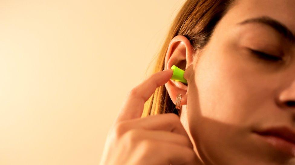 Woman putting ear plugs in