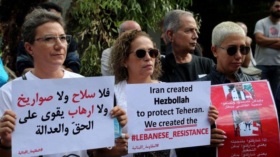 Protesters from the Lebanese Opposition Front carry placards and shout slogans against Hezbollah during a protest in front of the Palace of Justice in Beirut, Lebanon (19 October 2021)