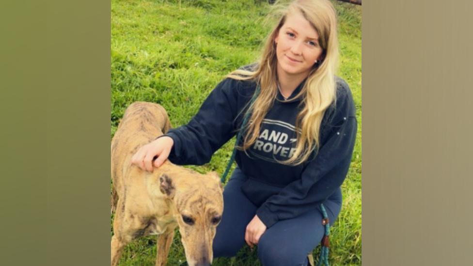 Image of Grace Vater. She is crouched down petting a dog.