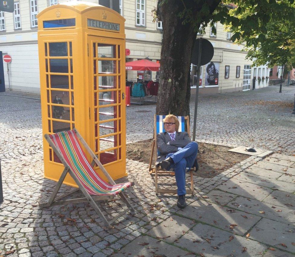 John Byford sitting next to a yellow phone box