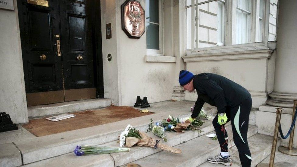 A man leaves flowers outside the French embassy as tribute to victims of Paris attacks, in London