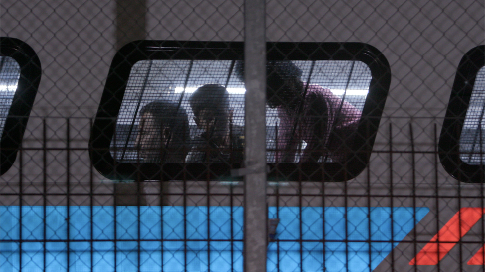 The outlines of some children are seen through the window of a bus in this photograph