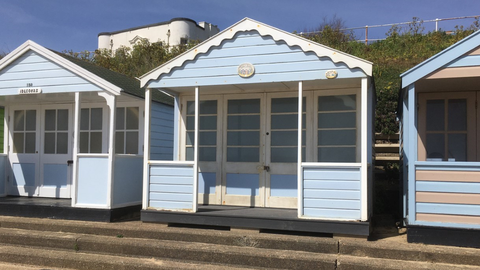 Three blue beach huts in a row