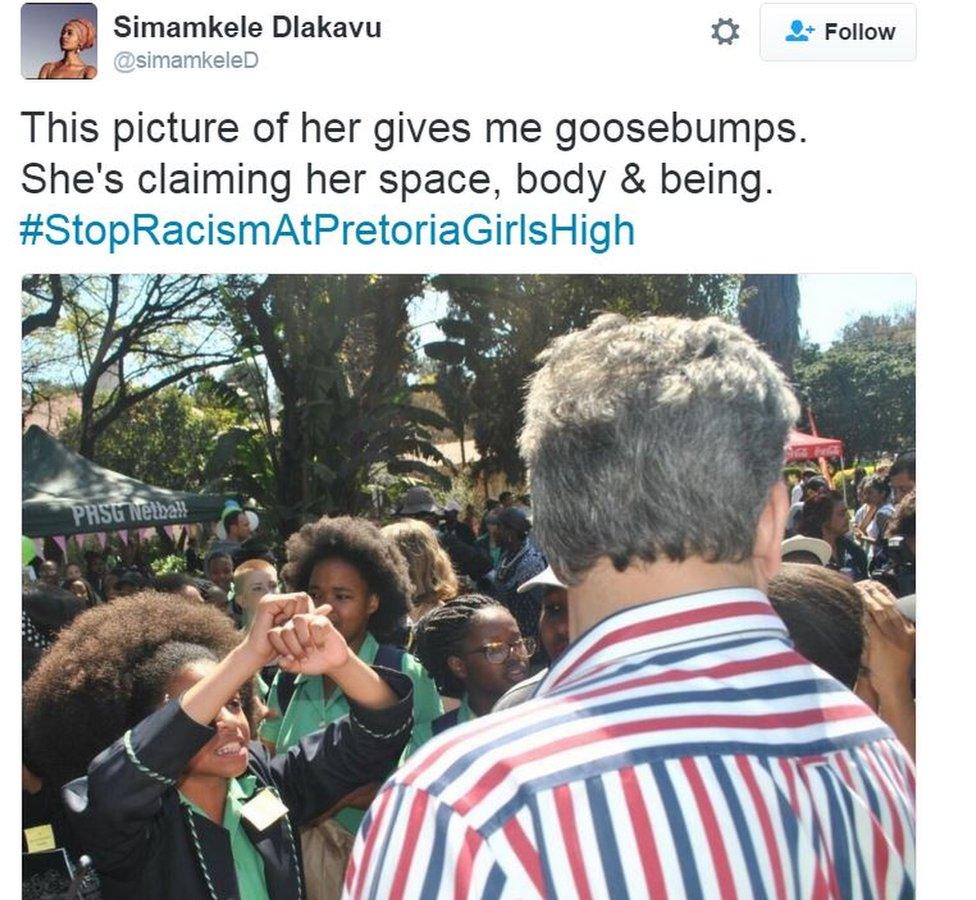 picture of young high school girl with afro crossing her arms in protest, standing in front of a white member of teaching staff