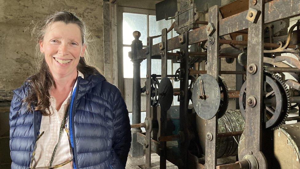 Woman standing beside clock mechanism