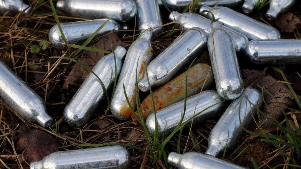 Laughing gas cannisters lie in the grass