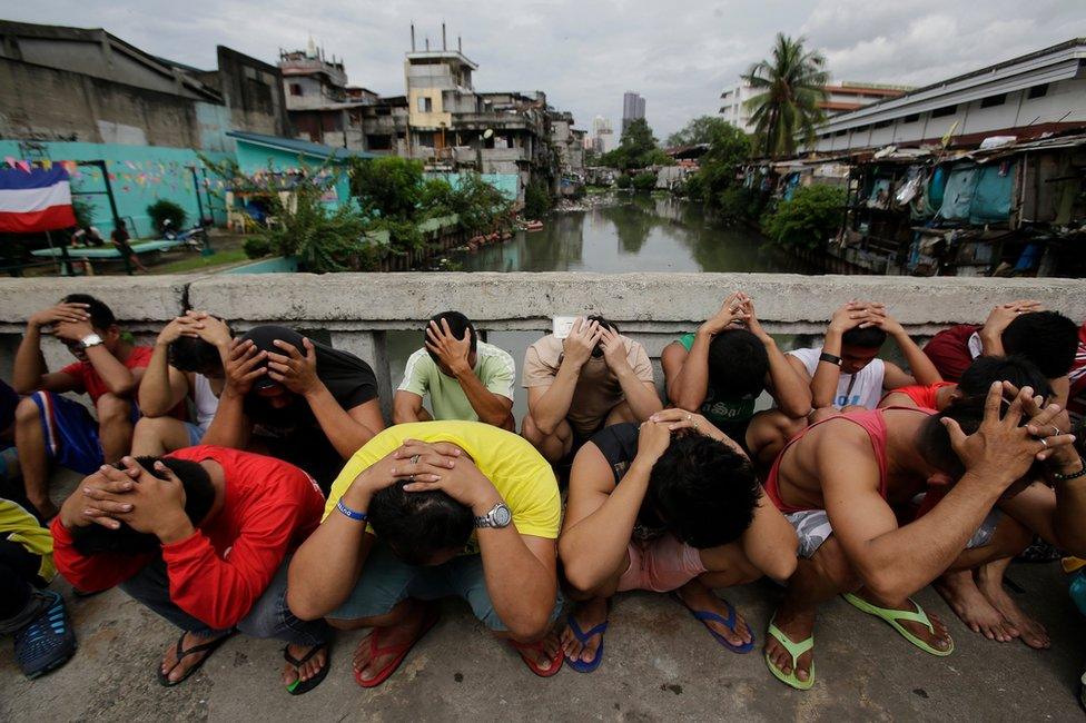 Filipino men place their hands over their heads as they are rounded up during a police operation as part of the continuing "War on Drugs" campaign of Philippine President Rodrigo Duterte in Manila, Philippines Friday 7 October 2016.