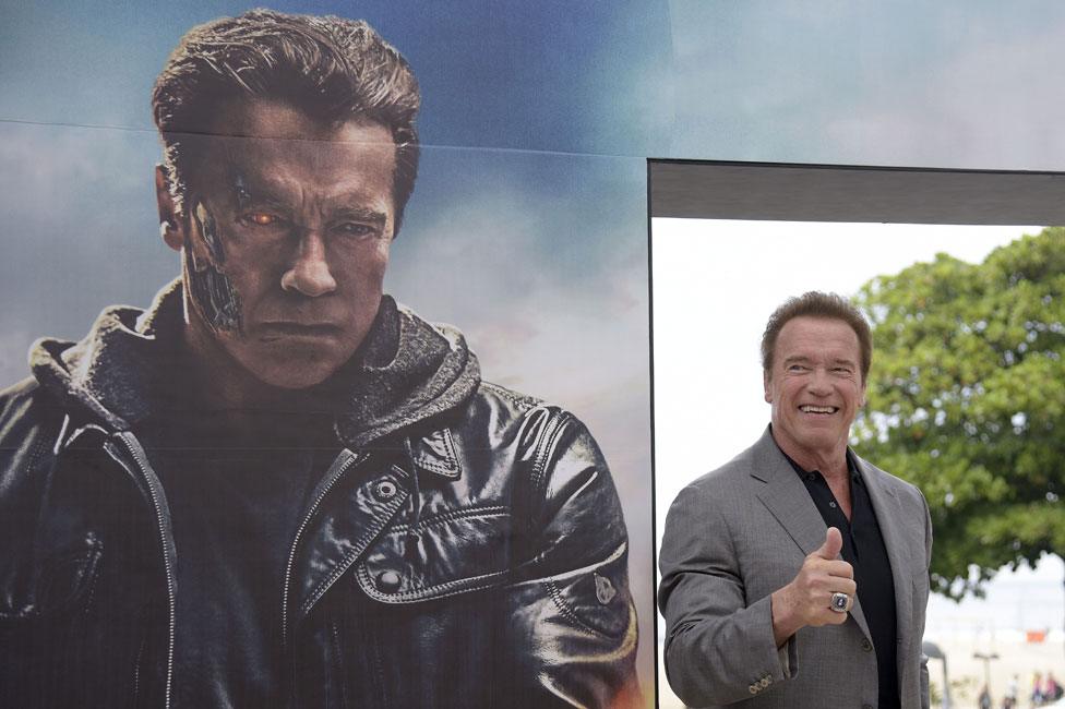 Arnold Schwarzenegger next to a Terminator Genisys hoarding