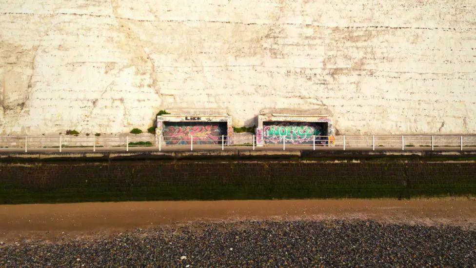 Two derelict shelters cut into the East Cliff in Ramsgate taken from the beack at low tide