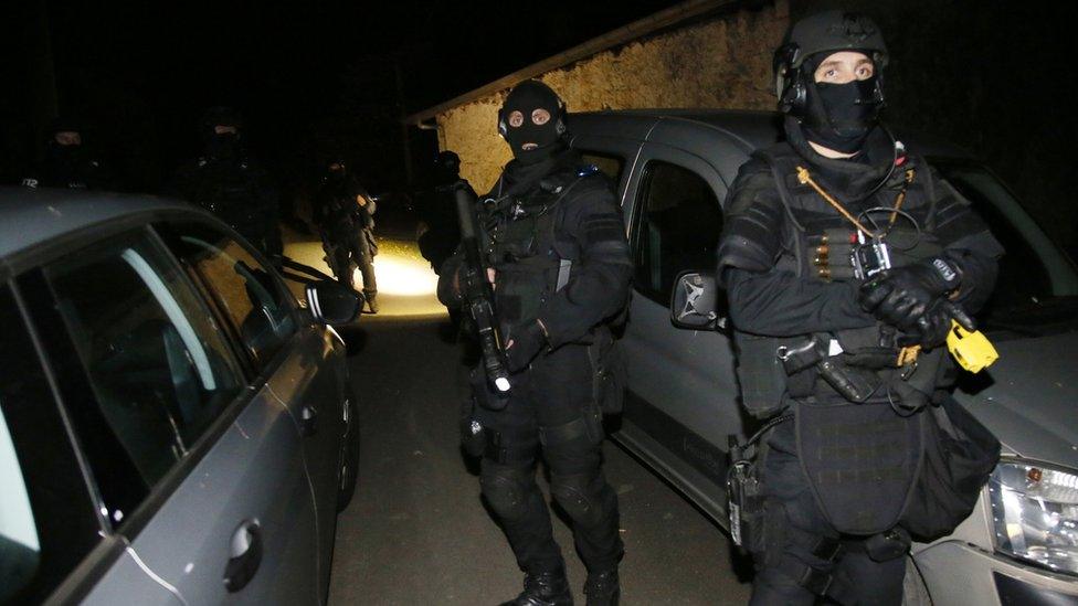 French police officers stand outside a house during a search operation in Louhossoa, south-western France, Friday, Dec 16, 2016