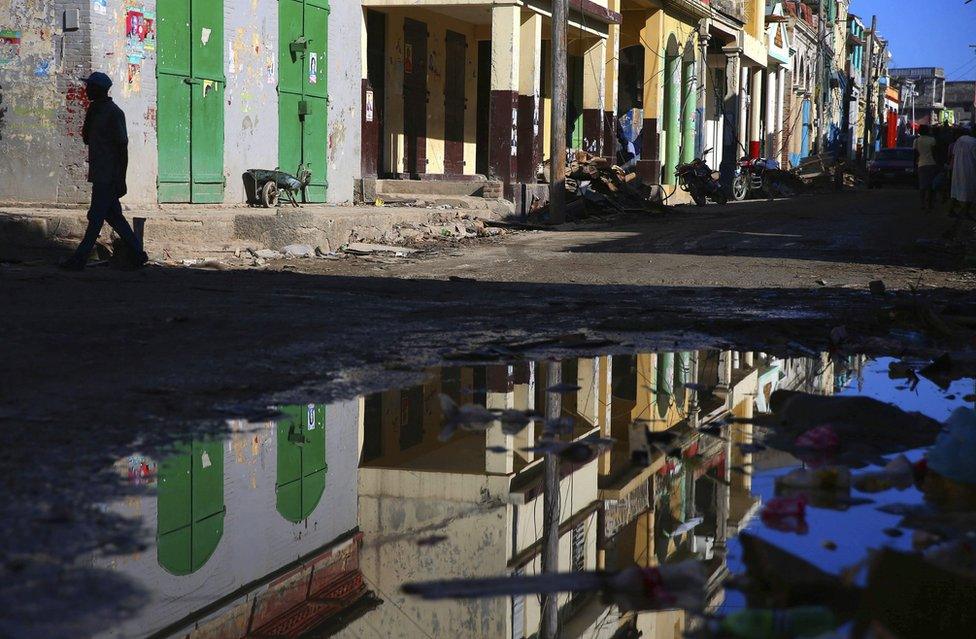 This picture shows a resident walking along a street covered with puddles in Jeremie, Haiti, on 12 October, 2016