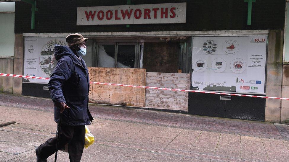 A man walks past a boarded up Woolworths in the UK in 2020