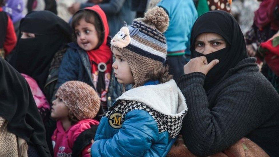 Displaced Syrians from Idlib province queue to receive food aid from a truck