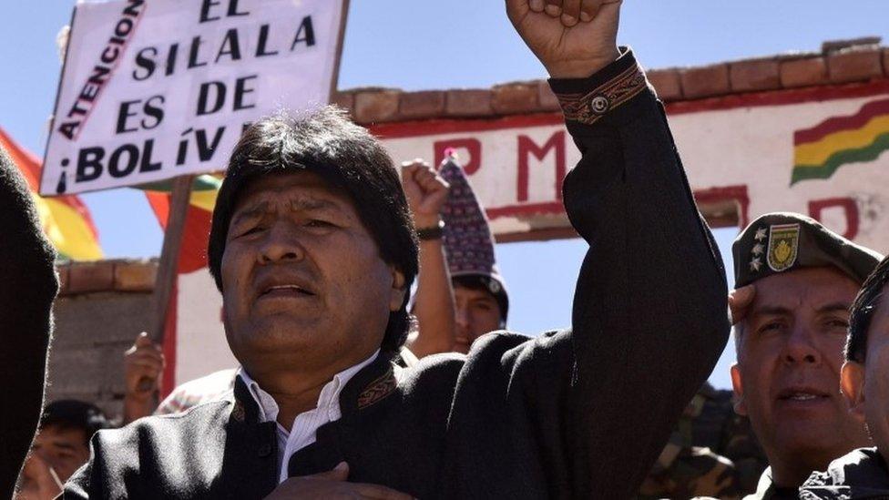 Bolivian President Evo Morales sings the national anthem next to a sign reading "The Silala is Bolivian" during a visit to the Silala springs, in Potosi department, southwestern Bolivia, 4 km away from the border with Chile, on March 29, 2016