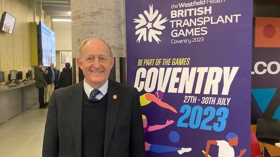 A man standing in front of a British Transplant Games banner