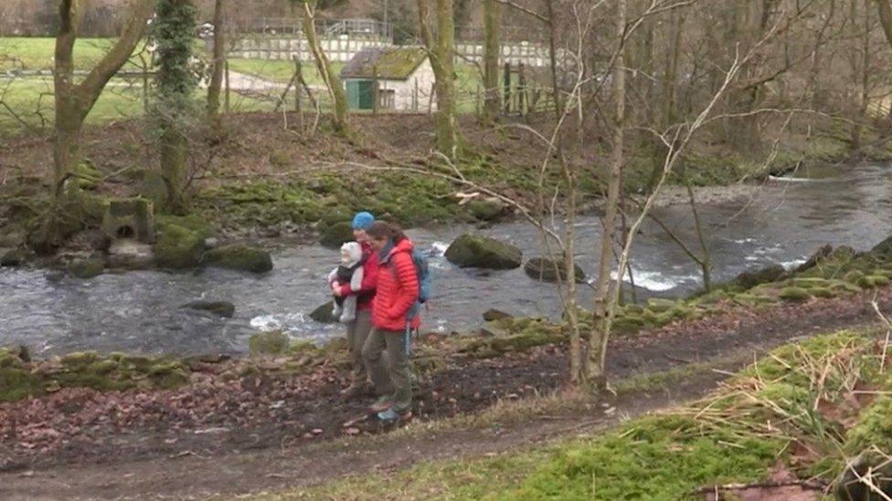 People walking along the River Kent bank near the Staveley water treatment works overflow pipe