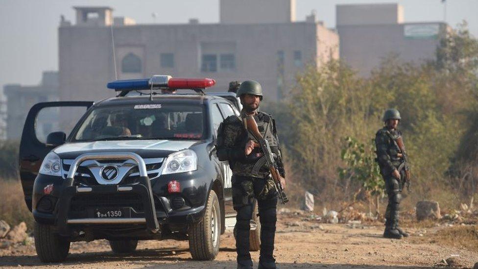 Pakistani security forces stand guard as supporters of Pakistan's former prime minister Nawaz Sharif gather outside the anti-corruption court in Islamabad on December 24, 2018