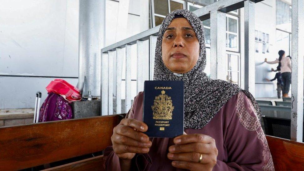 Palestinian-Canadian Seham al-Batnejy displays her passport as she waits at Rafah border crossing after evacuations were suspended following an Israeli strike on an ambulance, in Rafah in the southern Gaza Strip