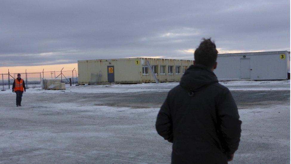 People stand near a reception centre for asylum seekers in Kirkenes, northern Norway, 11 November, 2015