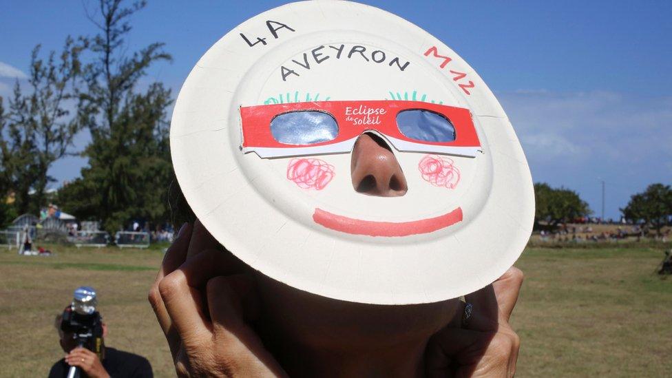 A woman looks through eclipse viewing glasses in Saint-Louis, on the island of La Reunion.