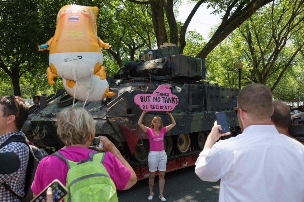 A protester stands next to a tank