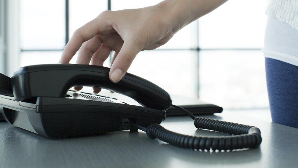 A woman picking up a landline phone