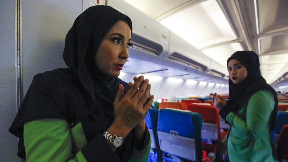 In this 22 December 2015, photo, Rayani Air flight crew pray before departure at Kuala Lumpur International Airport 2 in Sepang, Malaysia