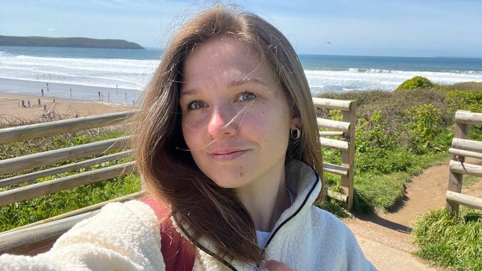 Woman with fence, beach and sea behind