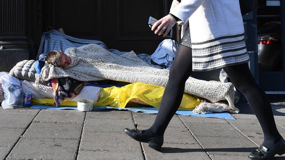 A woman walks past a rough sleeper