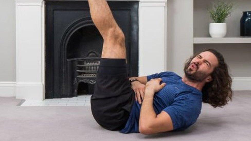 Joe Wicks pulling a face while doing sit-ups