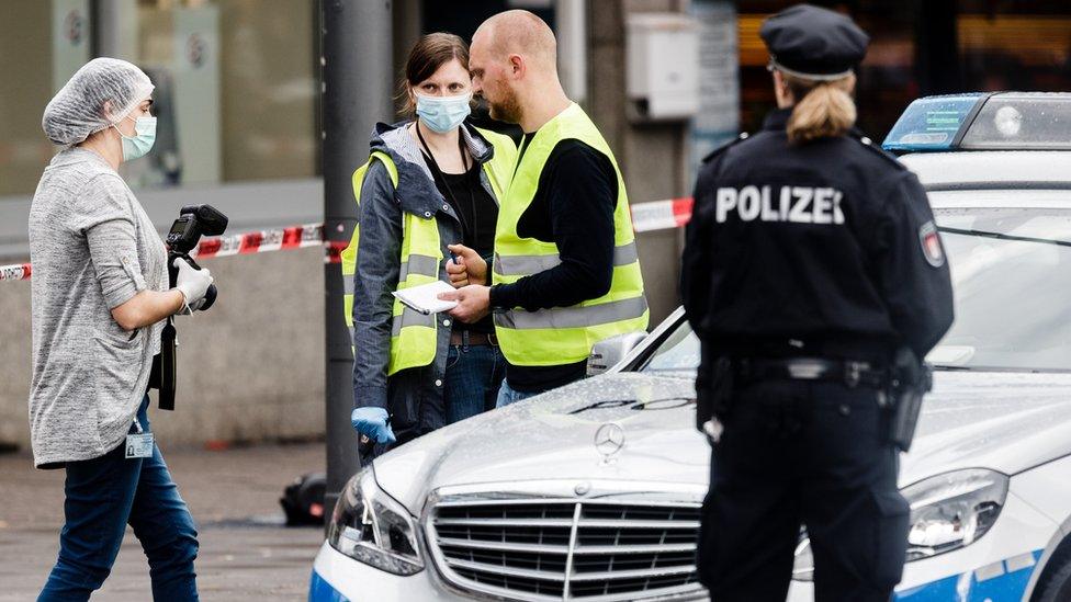 Police investigators search for evidence at the area around a supermarket in the northern German city of Hamburg, where a man killed one person and wounded several others in a knife attack, 28 July 2017