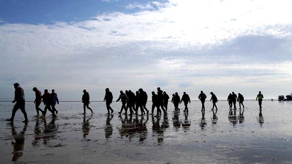 People walking across after alighting a boat which can be seen in the background