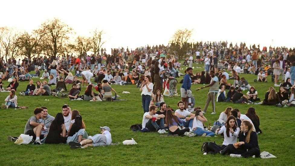 People enjoy the evening sunlight on Primrose Hill, north London, on Tuesday