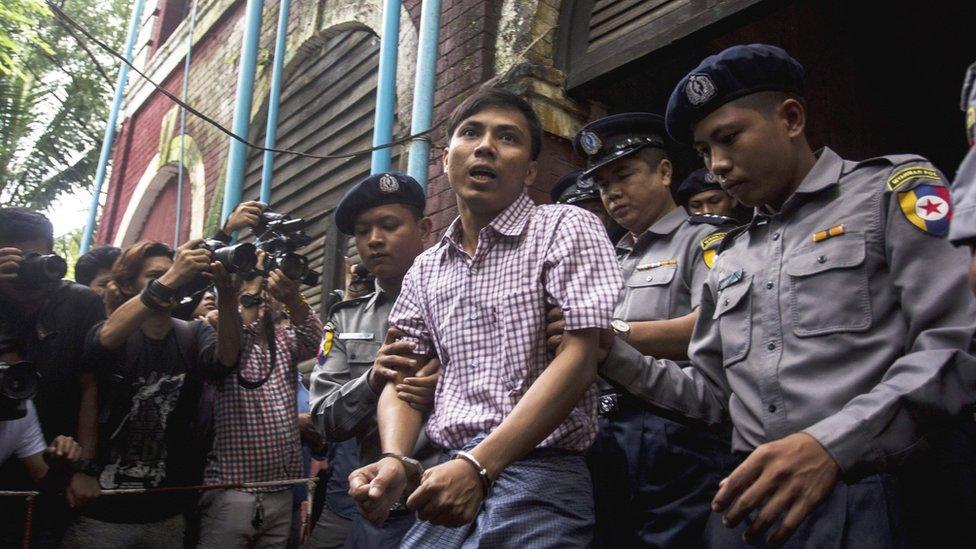 Kyaw Soe Oo (C) is escorted by police out of a court in Yangon on August 27, 2018