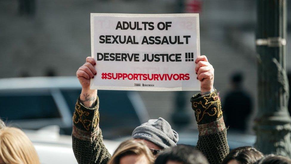 A demonstrator holds a sign overhead at a rally in support of the Adult Survivors Act on February 28, 2020 in New York City.