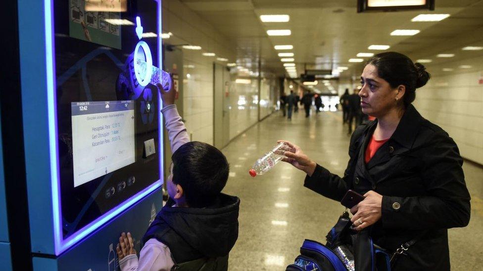 A boy recycling bottles into a machine