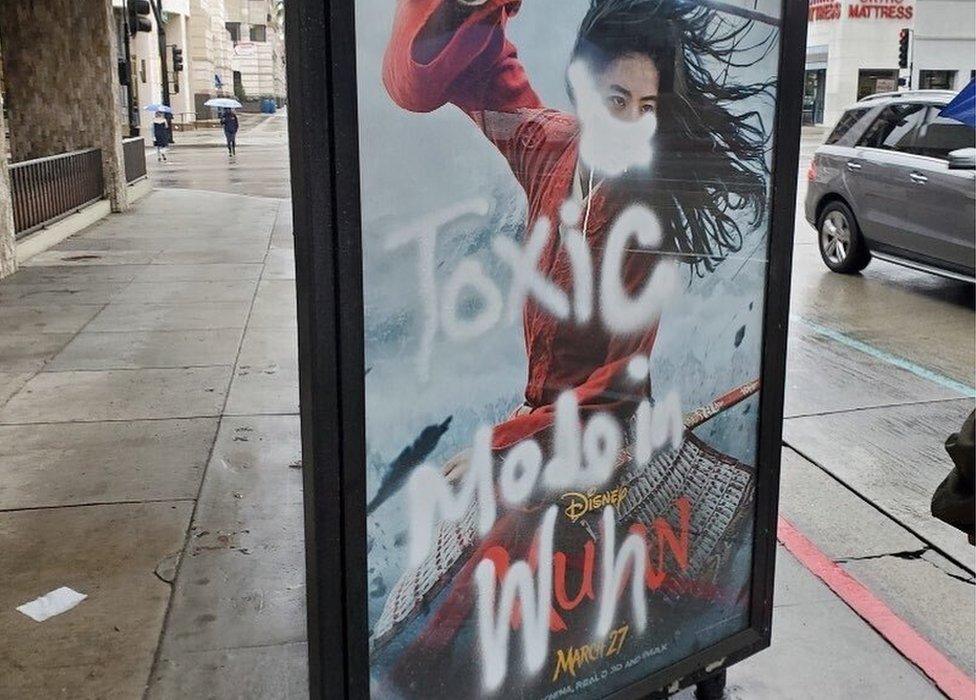 A Mulan film poster defaced with graffiti - a mask is painted over her face, along with the words "toxic made in Wuhan"