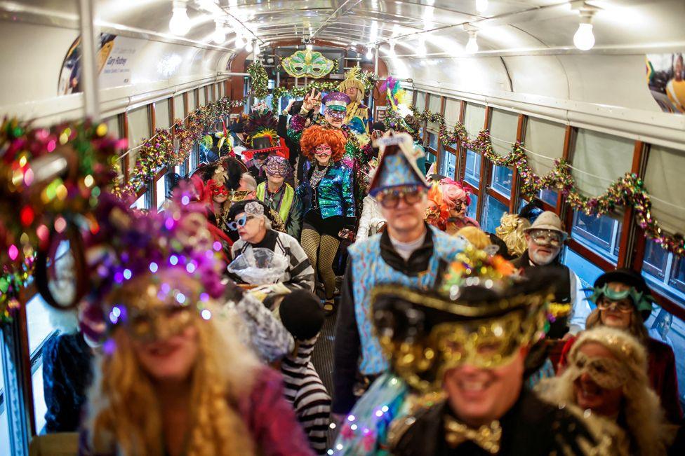 Revellers wearing fancy dress, masks and wigs inside a streetcar as part of a parade in New Orleans