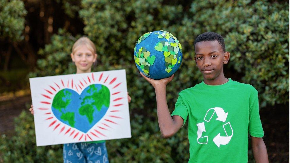 Two children hold up pictures of the Earth