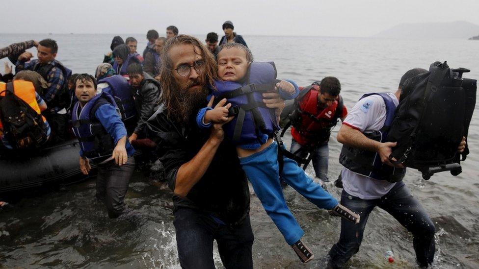 A volunteer carries a Syrian refugee child off an overcrowded dinghy at a beach after the migrants crossed part of the Aegean Sea from Turkey to the Greek island of Lesbos