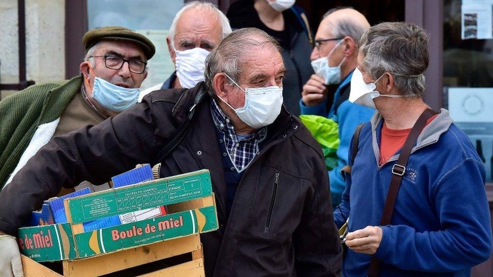 Wearing protective face masks, shoppers wait for their turn to enter the Cadillac market near the French city of Bordeaux on April 25, 2020